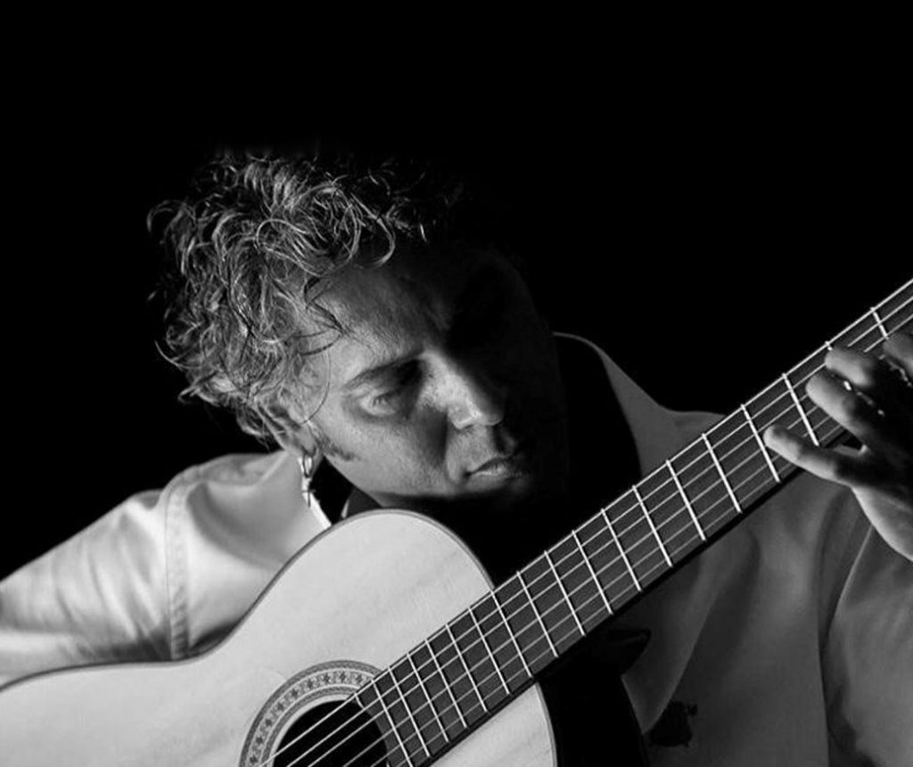 Black and white portrait of Curro Carrasco playing his guitar.